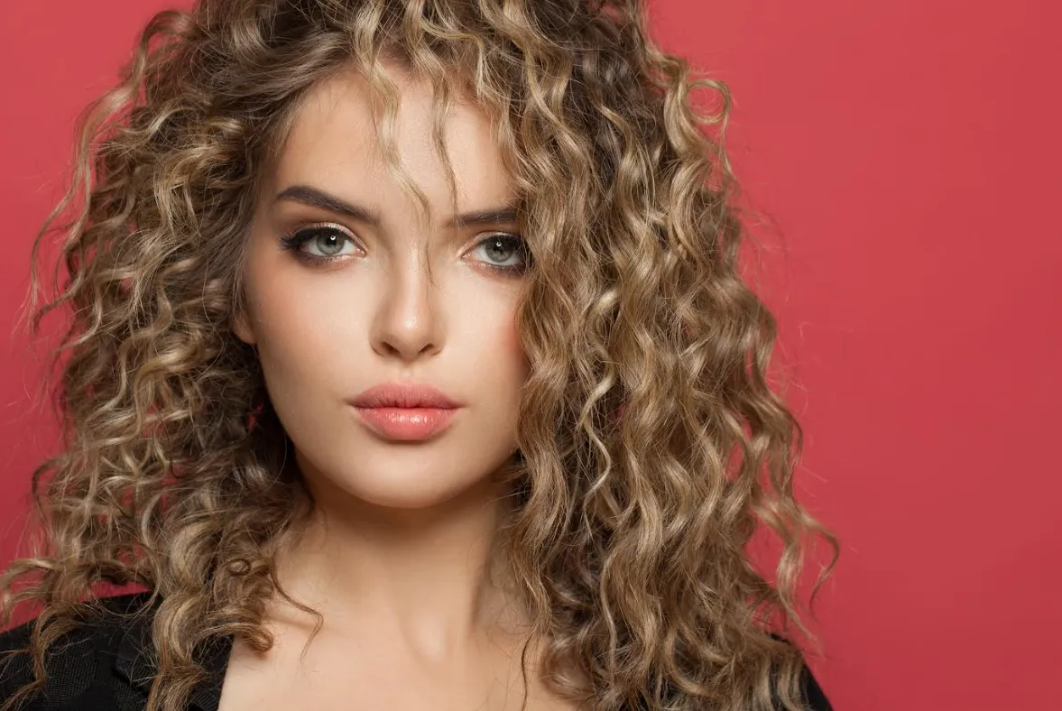 High quality natural looking human hair extensions on a woman with stunning, voluminous curly blonde hair.