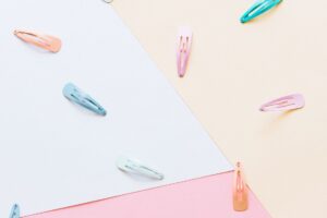 An artistic flat lay featuring colorful hair clips on a pastel geometric background.