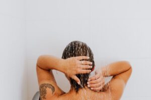 Woman enjoying a soothing shower with water cascading down, emphasizing relaxation and cleanliness.