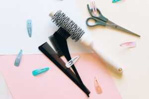 A flat lay of hairdressing tools on a pastel background, showcasing combs, brushes, and clips.